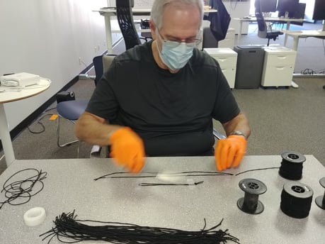 3DPPE employee assembling visor straps for printed face shields.