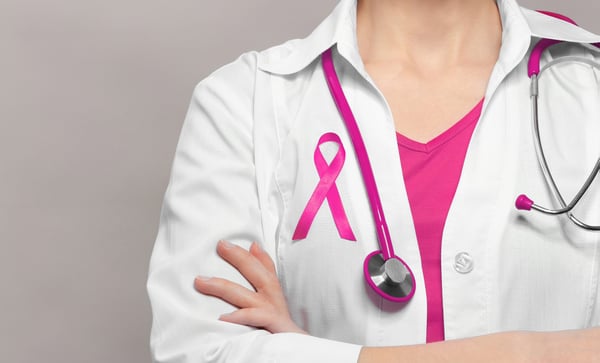 Image of a doctor with a stethoscope wearing a pink ribbon on her lab coat