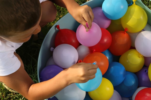 A camper grabbing a water balloon from a bucket