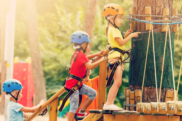 Kids in team colors lining up to take part in a climbing course as part of a Color War