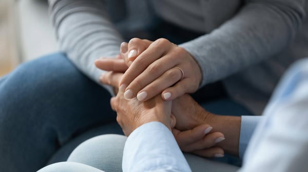 Image of two people holding hands in support