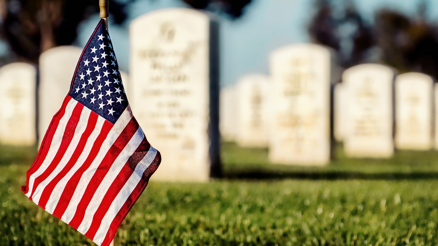 Close up of an American flag with military gravestones in the background