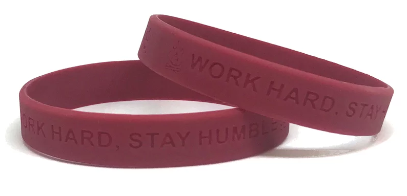 Maroon wristbands with the message "work hard stay humble" engraved on them