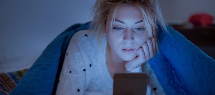 Sad girl reading her mobile phone in bed