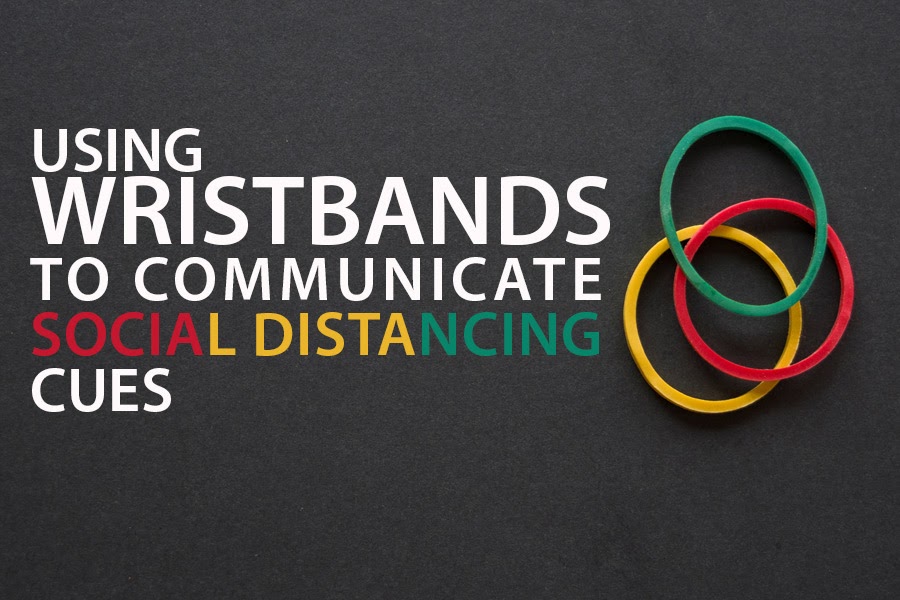 Black background with 3 wristbands. Text reads "Using wristbands to communicate social distancing cues."